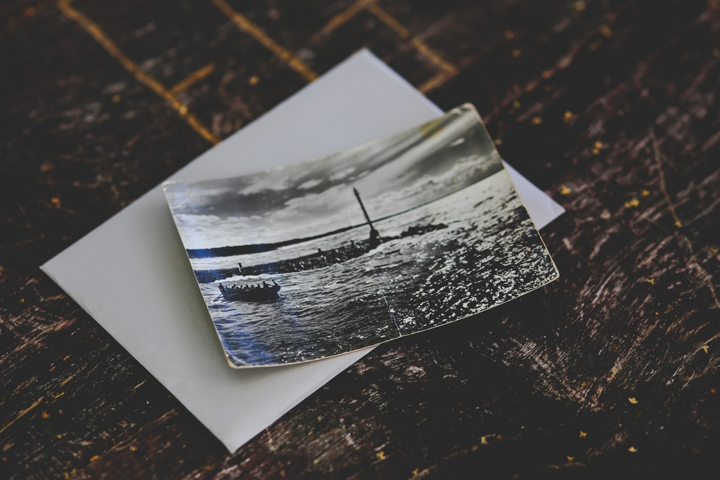 An old black-and-white photograph resting on an envelope on a dark wooden table