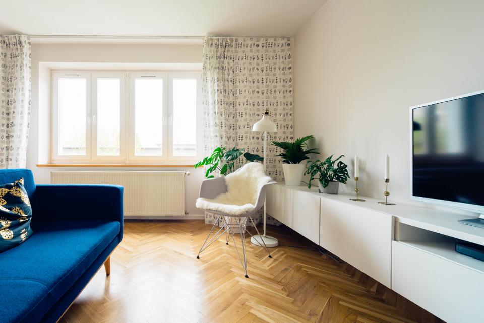 A bright living room with a blue sofa and a flat-screen TV on a white cabinet